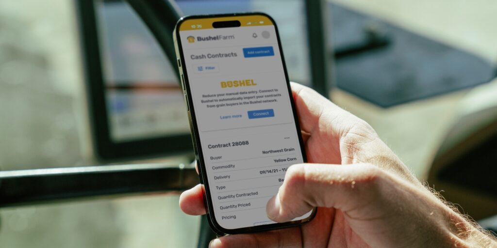 Person holding a phone with Bushel Farm contract feature showing